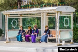 Women wait at a bus stop in Ashgabat in April 2018.