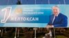A woman pushes a pram in front of a poster with a portrait of former Kazakh President Nursultan Nazarbayev as the country prepares to the Day of the First President, celebrated on December 1, in Almaty in 2015.
