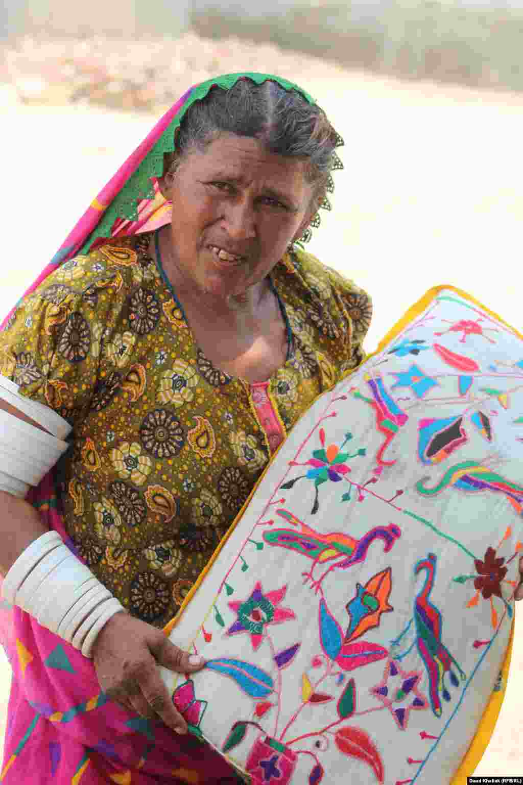 Kallan Bibi holds a handmade pillow case featuring Tharparkar's traditional embroidery.