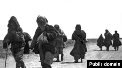Пытающиеся спастись от голода люди идут по дороге. 1930-е годы