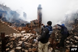 Membri ai misiunii OSCA fotografiază o casă distrusă de bombardamentele separatiste in Avdiivka, 25 februarie, 2017
