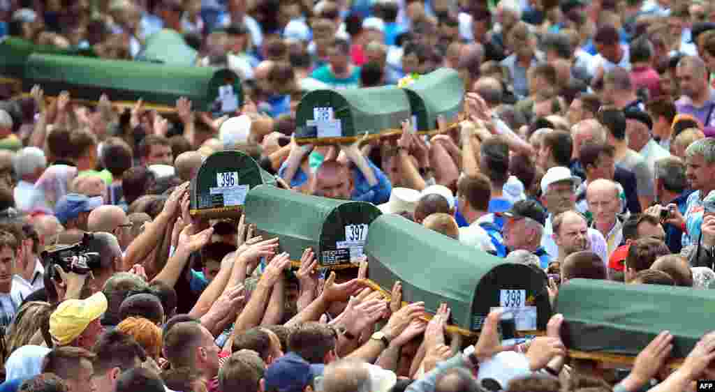 Bosnian Muslims carry caskets containing the bodies of people killed in the 1995 Srebrenica massacre as they prepare for a mass burial during a memorial ceremony in the village of Potocari on July 11, the 18th anniversary of the killings. (AFP/Elvis Barukcic)