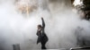 An Iranian woman raises her fist amid the smoke of tear gas at the University of Tehran during a protest driven by anger over economic problems in the capital on December 30.