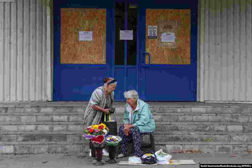 Women sell flowers and vegetables near a closed supermarket. In Pokrovsk, all large supermarkets and shopping centers are closed. Only small grocery stores remain open.