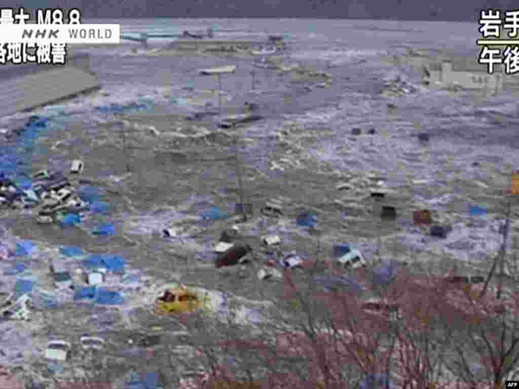 Japan--screen grab shows cars and containers floating in a massive tsunami wave to have hit Sendai, 11Mar2011 - Скриншот выпуска новостей телекомпании NHK 11 марта 2011. Вагоны и контейнеры плавают в волне цунами. JAPAN OUT AFP PHOTO / HO / NHK
