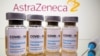 Vials with a sticker reading "COVID-19 / Coronavirus vaccine / Injection only" and a medical syringe are seen in front of a displayed AstraZeneca logo. October 31, 2020. 