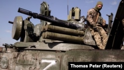 A Ukrainian soldier sits atop a Russian artillery vehicle marked with the 'Z' symbol that Ukraine captured during fighting outside Kharkiv in March.