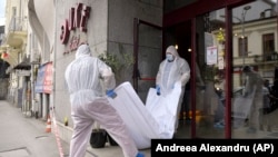 Forensic workers carry the body of Gholamreza Mansuri from the Duke Hotel in downtown Bucharest.