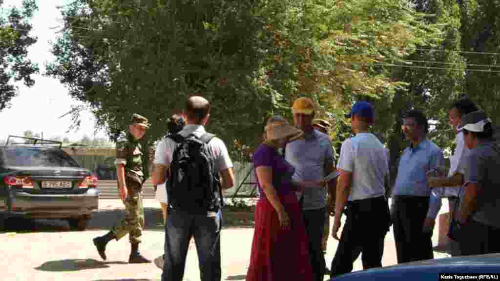 Қамауда отырған оппозициялық саясаткер Владимир Козловты құттықтау үшін түрме алдына келген адамдардың жанынан өтіп бара жатқан ішкі істер әскери қызметкері. Заречный кенті, Алматы облысы, 10 тамыз 2014 жыл.