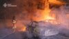 This handout picture taken and released by Ukrainian State Emergency Service on June 12, 2025 shows firefighters putting out burning vehicles parked outside a residential building destroyed during a Russian drone strike overnight in Kharkiv. 