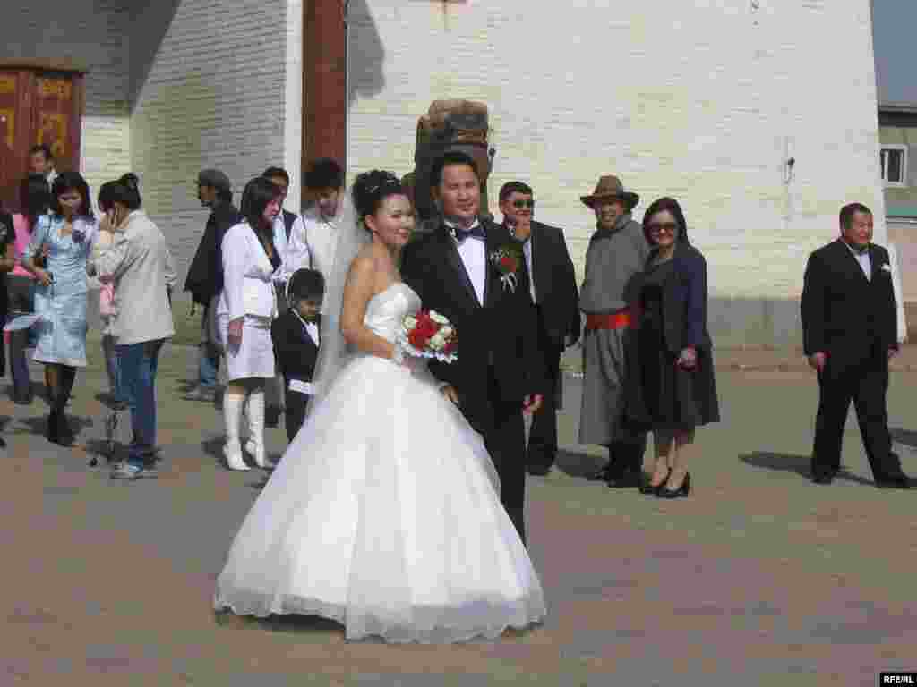 Newlyweds pose outside the monastery. - Mongolians often plan their personal lives around auspicious dates on the Buddhist calendar, and brides and grooms often include a monastery in the sites they visit for photographs after the wedding ceremony.