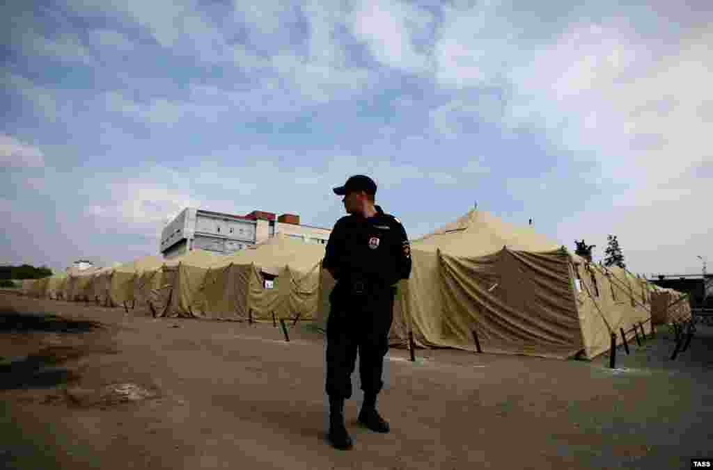 A Russian police officer stands guard at a tent camp for illegal migrant workers at the site of Moscow's former Cherkizovsky market in August. City authorities closed the market in 2009, alleging numerous illegal activities and safety violations. 