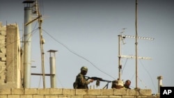 An image provided to AP by a citizen jouralist in May of Syrian soldiers on the roof of a building at an undisclosed location.