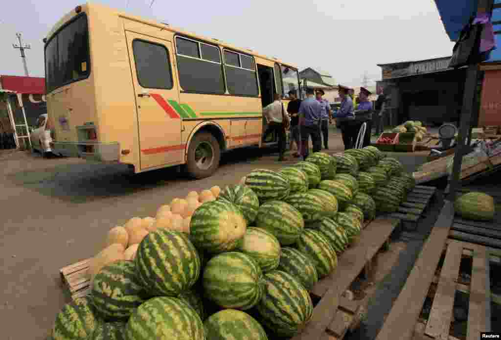 Police officers escort detained migrant workers to a police bus following an unannounced document check at a market in the Siberian city of Krasnoyarsk in August 2013. 