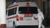 Armenia -- A medical worker clad in protecive gear and an ambulance parked at the entrance to Surp Grigor Lusavorich hospital, Yerevan, April 8, 2020.