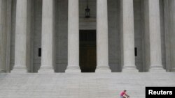 Egy nő kerékpározik az Egyesült Államok Legfelsőbb Bírósága előtt Washingtonban 2021. szeptember 1-jén